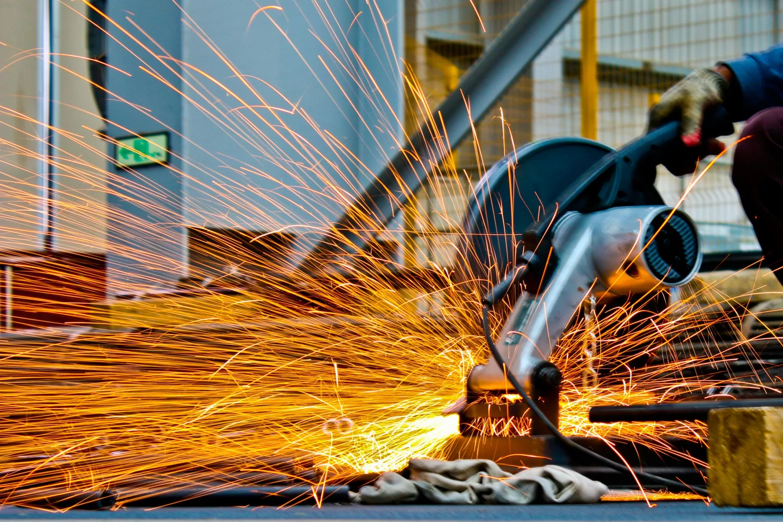 Worker using an angle grinder, producing a shower of sparks.